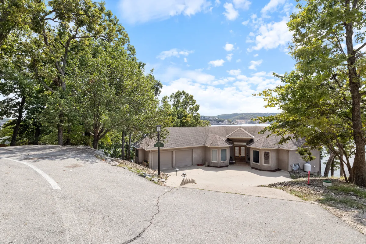 The home's exterior is nestled among tall trees, with a spacious driveway and a welcoming porch. The surrounding landscape offers plenty of room for outdoor gatherings, nature walks, and supervised play, all in a relaxed, natural setting.