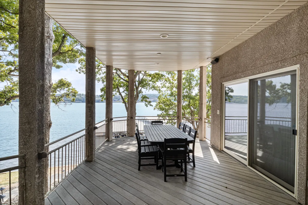 An inviting outdoor dining area featuring a large table set on a deck, surrounded by trees and overlooking a beautiful lake. The serene waters and natural scenery provide a scenic backdrop, ideal for group meals or evening gatherings.