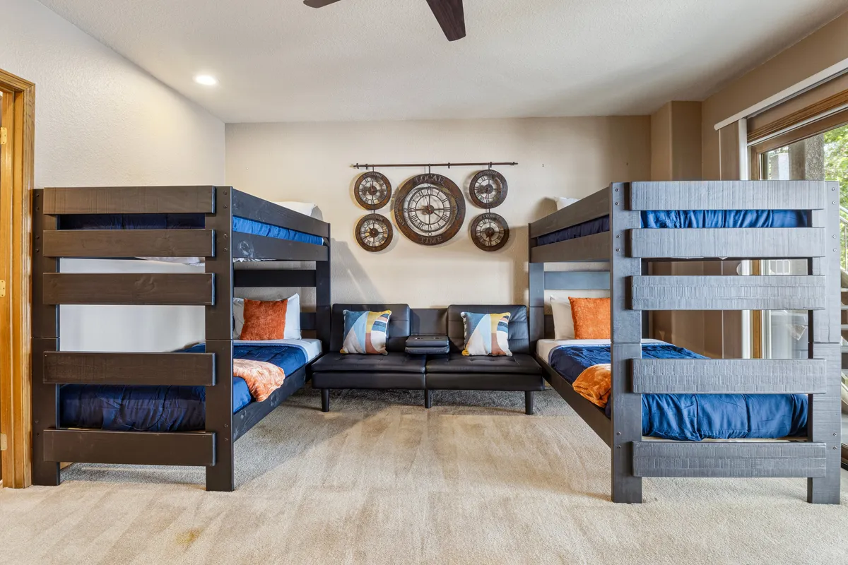 A comfortable bedroom featuring bunk beds, a sofa, and playful wall decor, designed for both relaxation and group activities like late-night chats or movie nights. The space is friendly and inviting, perfect for children or group stays.