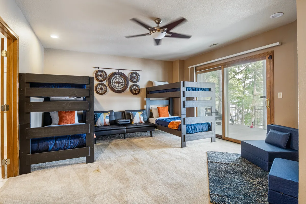 A fun, spacious bedroom setup with bunk beds, a sofa, decorative wall art, and large windows. The room is designed for groups or families, offering flexible sleeping arrangements, perfect for children or friends traveling together.