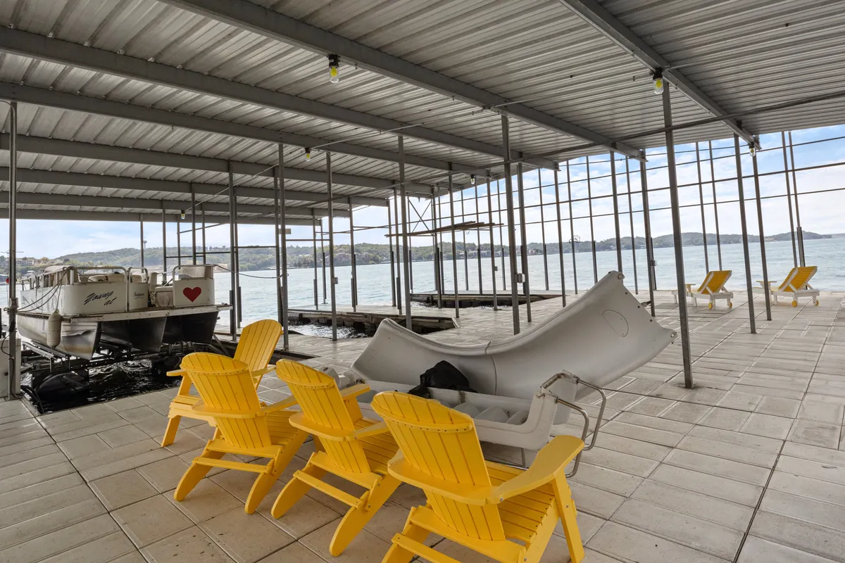 This scene showcases yellow Adirondack chairs arranged along the water's edge, with boats bobbing nearby and a wide view of the lake. The setting encourages relaxation, social gatherings, and enjoying sunrises or sunsets by the water.